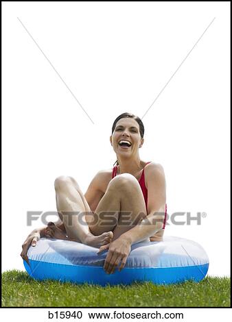 Woman sitting cross legged in swimming ring on grass laughing View Large Photo Image Stock Image - Woman sitting cross legged in swimming ring on grass laughing. Fotosearch