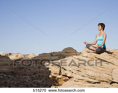 Woman sitting cross legged on rock outdoors doing yoga View Large Photo Image Stock Image - Woman sitting cross legged on rock outdoors doing yoga. Fotosearch