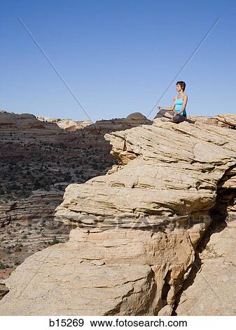 Woman sitting cross legged on rock outdoors doing yoga View Large Photo Image Stock Photo - Woman sitting cross legged on rock outdoors doing yoga. Fotosearch