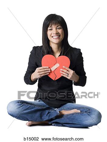 Woman sitting cross legged with mended red heart smiling View Large Photo Image Stock Image - Woman sitting cross legged with mended red heart smiling. Fotosearch