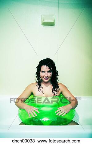 Woman sitting in bathtub with inflatable ring smiling View Large Photo Image Stock Photo - Woman sitting in bathtub with inflatable ring smiling. Fotosearch