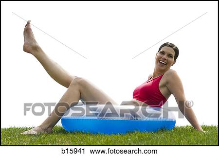 Woman sitting in swimming ring on grass with leg up smiling View Large Photo Image Stock Image - Woman sitting in swimming ring on grass with leg up smiling. Fotosearch