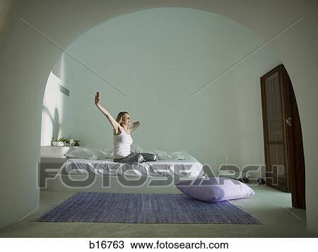 Woman sitting on bed stretching View Large Photo Image Stock Image - Woman sitting on bed stretching. Fotosearch
