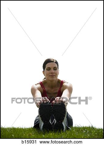 Woman sitting on grass outdoors stretching View Large Photo Image Stock Image - Woman sitting on grass outdoors stretching. Fotosearch