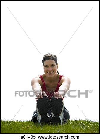 Woman sitting on grass stretching and smiling View Large Photo Image Stock Photography - Woman sitting on grass stretching and smiling. Fotosearch