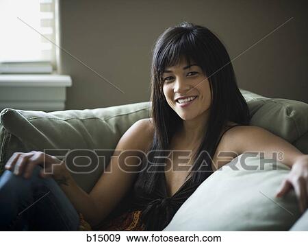 Woman sitting on sofa smiling View Large Photo Image Stock Photo - Woman sitting on sofa smiling. Fotosearch