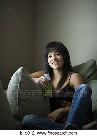 Woman sitting on sofa with beverage smiling View Large Photo Image Stock Image - Woman sitting on sofa with beverage smiling. Fotosearch