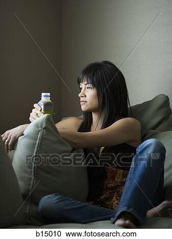 Woman sitting on sofa with bottle View Large Photo Image Stock Image - Woman sitting on sofa with bottle. Fotosearch