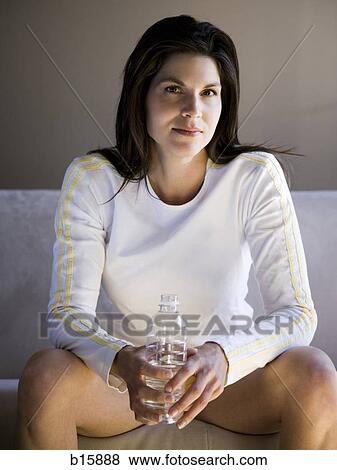 Woman sitting on sofa with bottled water View Large Photo Image Stock Photo - Woman sitting on sofa with bottled water. Fotosearch