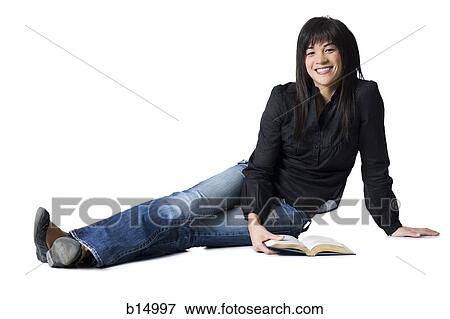 Woman sitting with legs outstretched with hardcover book smiling View Large Photo Image Stock Photo - Woman sitting with legs outstretched with hardcover book smiling. Fotosearch