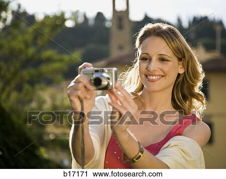 Woman smiling and taking a photograph outdoors View Large Photo Image Stock Image - Woman smiling and taking a photograph outdoors. Fotosearch
