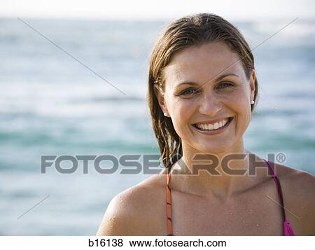 Stock Photo - Woman smiling outdoors with water in background. Fotosearch