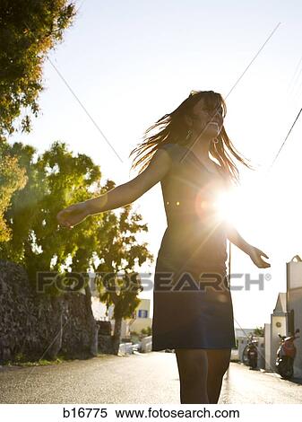 Woman standing on street in silhouette with arms up backlit View Large Photo Image Stock Photography - Woman standing on street in silhouette with arms up backlit. Fotosearch
