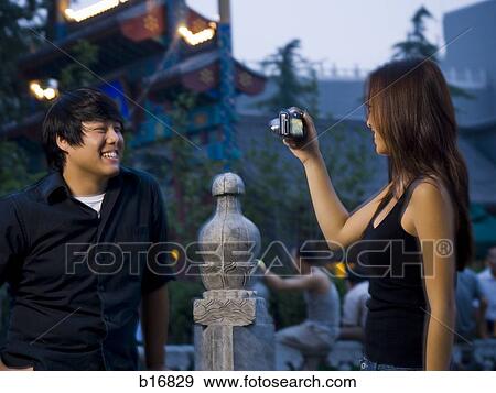 Stock Photo - Woman taking photo of man outdoors with digital camera. Fotosearch
