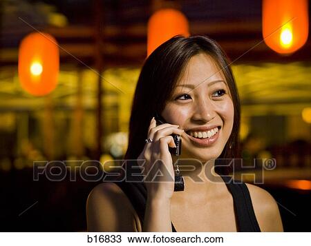 Woman talking on a cell phone outdoors at night smiling View Large Photo Image Stock Image - Woman talking on a cell phone outdoors at night smiling. Fotosearch