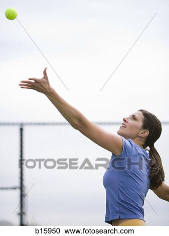 Woman tossing tennis ball in air to serve View Large Photo Image Stock Image - Woman tossing tennis ball in air to serve. Fotosearch