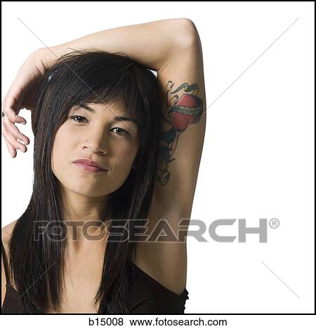 Stock Photo - Woman with arm resting on head and heart tattoo. Fotosearch