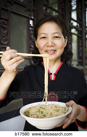 Woman with bowl of noodles and chopsticks smiling View Large Photo Image Stock Image - Woman with bowl of noodles and chopsticks smiling. Fotosearch