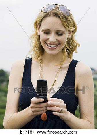 Woman with cell phone outdoors smiling View Large Photo Image Stock Photo - Woman with cell phone outdoors smiling. Fotosearch