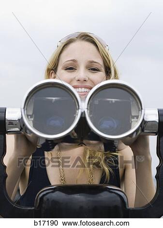 Stock Image - Woman with coin operated binoculars smiling. Fotosearch
