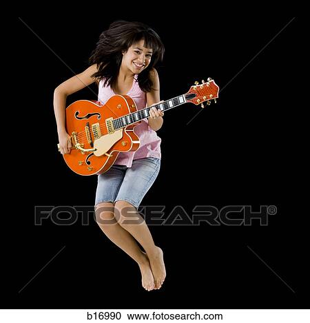 Stock Image - Woman with guitar leaping and smiling. Fotosearch