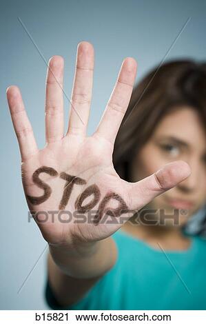 Stock Image - Woman with hand up and stop written on it. Fotosearch