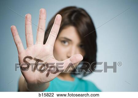 Stock Image - Woman with hand up and stop written on it. Fotosearch