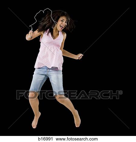 Stock Image - Woman with mp3 player leaping and smiling. Fotosearch