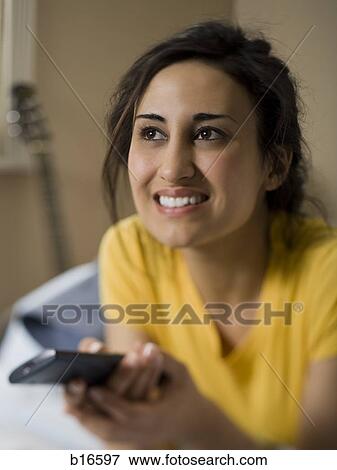 Woman with remote control smiling View Large Photo Image Stock Photo - Woman with remote control smiling. Fotosearch