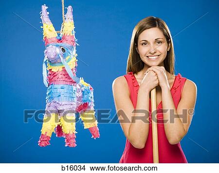 Woman with stick standing beside pinata smiling View Large Photo Image Picture - Woman with stick standing beside pinata smiling. Fotosearch