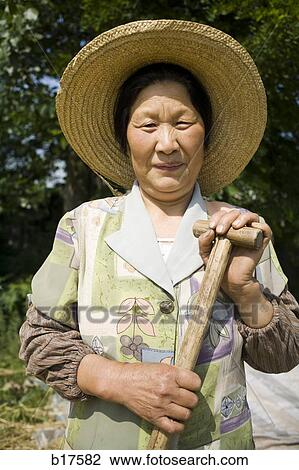 Woman with straw hat and shovel standing outdoors smiling View Large Photo Image Stock Image - Woman with straw hat and shovel standing outdoors smiling. Fotosearch