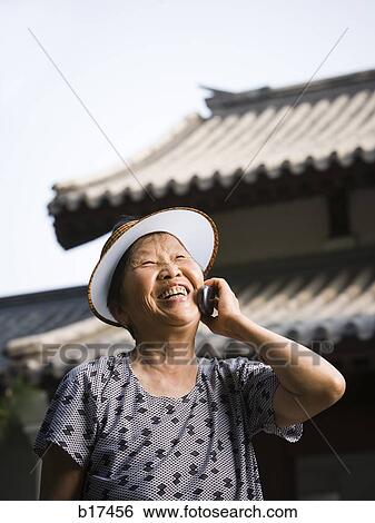 Woman with sun visor outdoors smiling talking on cell phone View Large Photo Image Stock Photograph - Woman with sun visor outdoors smiling talking on cell phone. Fotosearch