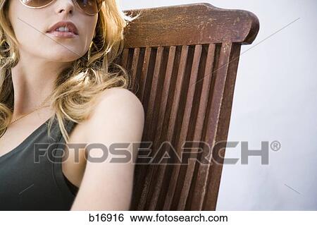 Woman with sunglasses sitting in wooden chair outdoors View Large Photo Image Stock Photograph - Woman with sunglasses sitting in wooden chair outdoors. Fotosearch