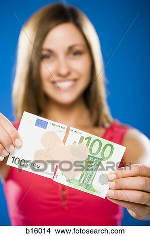 Picture - Woman with torn one hundred dollar euro banknote with plastic strips. Fotosearch