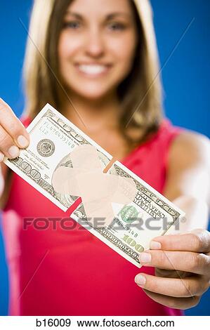 Stock Photo - Woman with torn one hundred dollar American banknote with plastic strip. Fotosearch