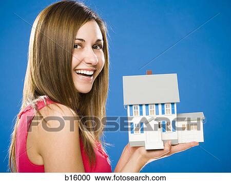 Stock Image - Woman with toy house smiling. Fotosearch