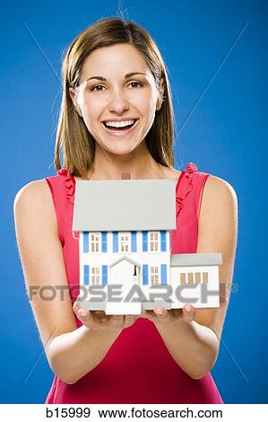 Stock Photo - Woman with toy house smiling. Fotosearch