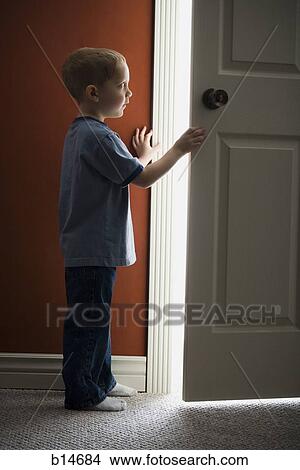 Picture - Young boy looking through doorway. Fotosearch