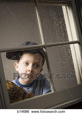 Young boy with baseball glove looking out window on rainy day View Large Photo Image Stock Photograph - Young boy with baseball glove looking out window on rainy day. Fotosearch