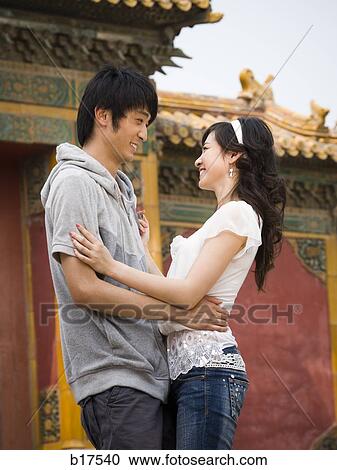 Young couple embracing and smiling outdoors View Large Photo Image Stock Image - Young couple embracing and smiling outdoors. Fotosearch
