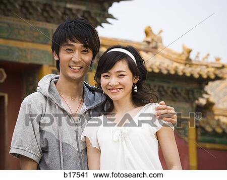 Young couple embracing and smiling outdoors View Large Photo Image Stock Image - Young couple embracing and smiling outdoors. Fotosearch