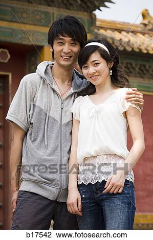 Young couple embracing and smiling outdoors View Large Photo Image Stock Image - Young couple embracing and smiling outdoors. Fotosearch