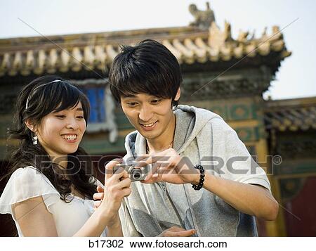 Young couple taking a photograph outdoors smiling View Large Photo Image Stock Image - Young couple taking a photograph outdoors smiling. Fotosearch
