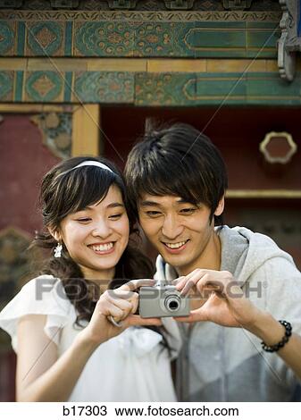 Young couple taking a photograph outdoors smiling View Large Photo Image Stock Image - Young couple taking a photograph outdoors smiling. Fotosearch