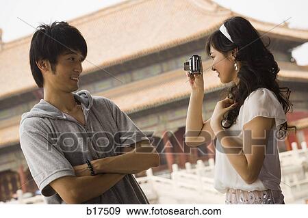 Stock Photo - Young couple taking a photograph outdoors smiling. Fotosearch