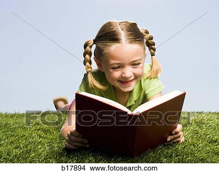 Young girl reading a book on grass. View Large Photo Image Picture - Young girl reading a book on grass.. Fotosearch