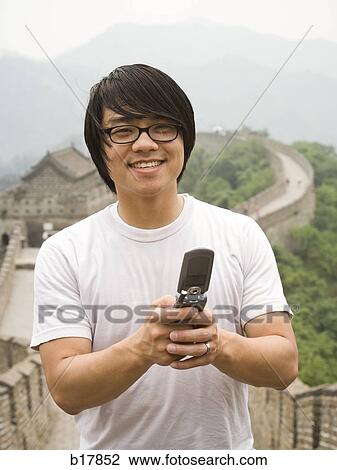Young man at the Great Wall of China on a mobile phone. View Large Photo Image Stock Image - Young man at the Great Wall of China on a mobile phone.. Fotosearch