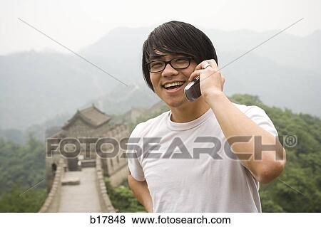 Young man at the Great Wall of China on a mobile phone. View Large Photo Image Stock Photo - Young man at the Great Wall of China on a mobile phone.. Fotosearch