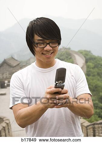 Young man at the Great Wall of China on a mobile phone. View Large Photo Image Stock Photo - Young man at the Great Wall of China on a mobile phone.. Fotosearch