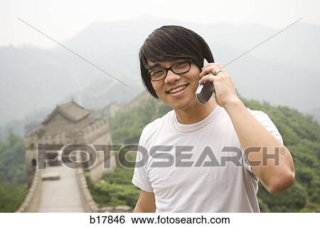 Young man at the Great Wall of China on a mobile phone. View Large Photo Image Stock Photograph - Young man at the Great Wall of China on a mobile phone.. Fotosearch